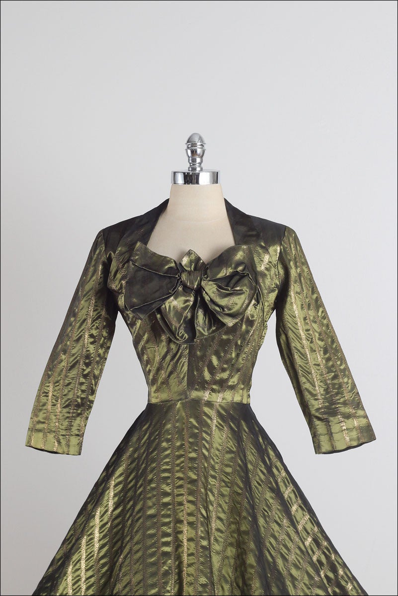 ➳ vintage 1950s dress

* metallic green sharkskin taffeta
* gold stripe threading
* full skirt
* metal side zipper
* by Donald Originals

condition | excellent

fits like xs/s

length 47