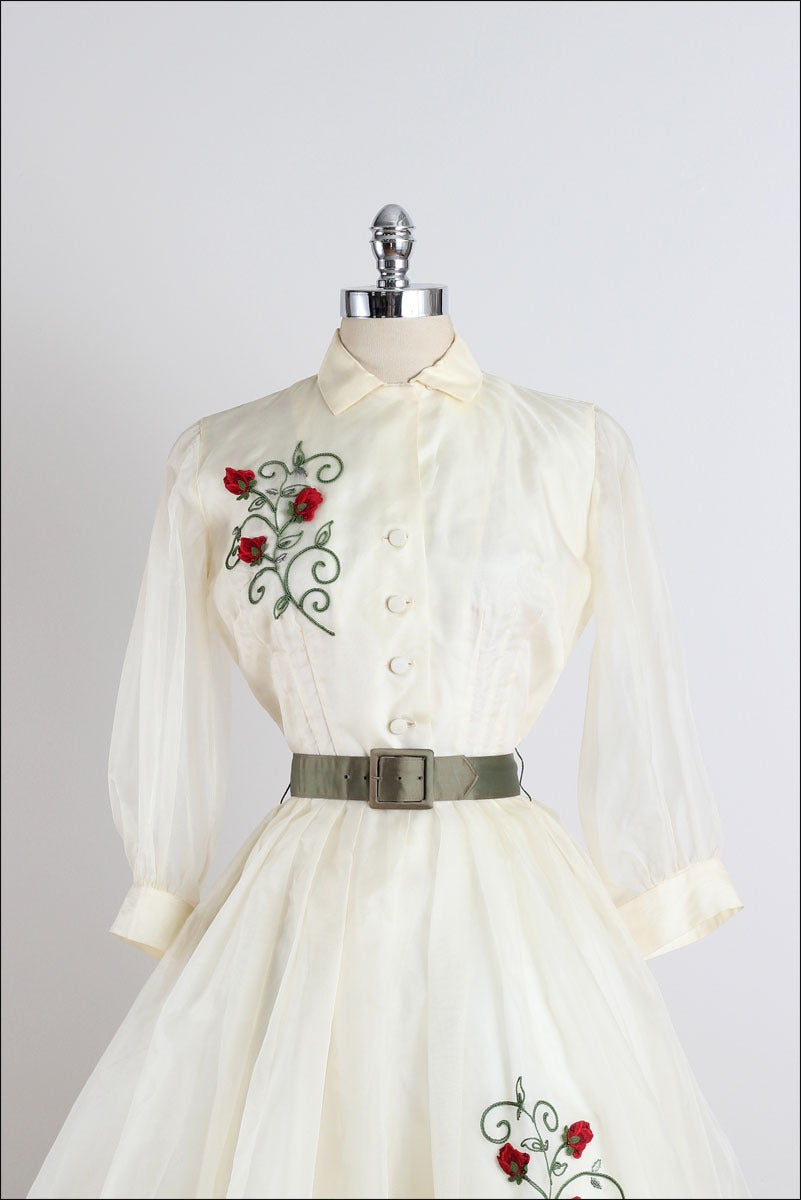 ➳ vintage 1960s dress

* ivory organza
* acetate lining
* sheer sleeves
* detachable tulle crinoline
* button front
* detached belt
* red rose appliques
* by Topsey Originals
** This dress originally belonged to a lady named Vrina Grimes