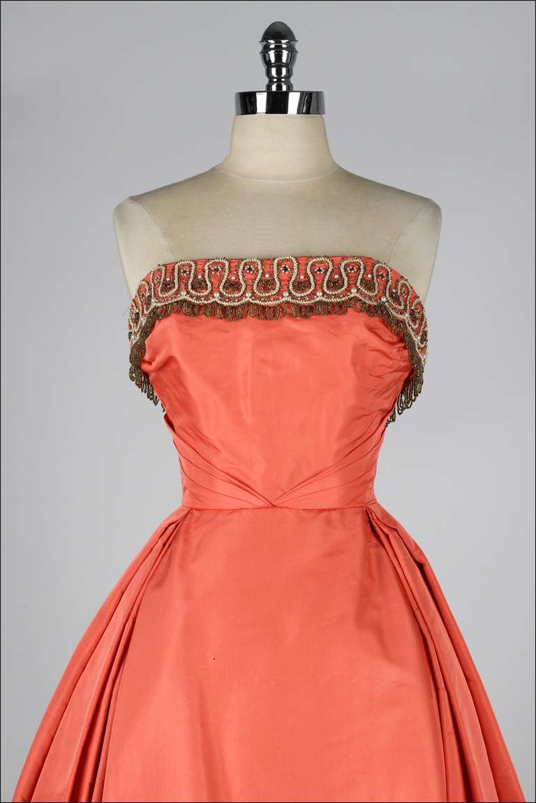 vintage 1950's dress

* salmon color silk taffeta
* beautiful beaded fringe
* strapless bodice with stays
* tulle skirt lining
* metal back zipper
* spaghetti straps can be worn in or out
* Minuet by Mollie Stone

condition |