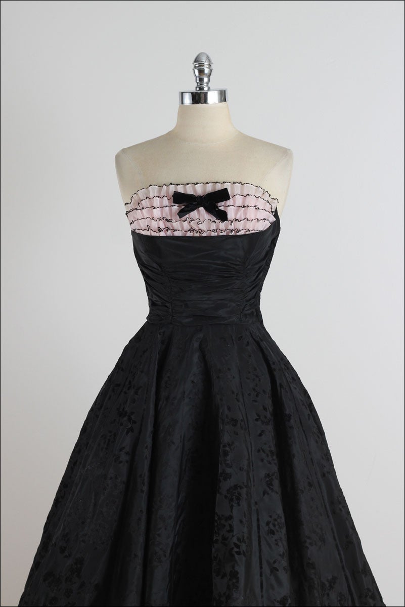 ➳ vintage 1950s dress

* black acetate flocked floral skirt
* tulle lining
* pink chiffon ruffled bodice
* bodice stays
* bow tie accent
* metal side zipper

condition | excellent 

fits like xs

dress length 41