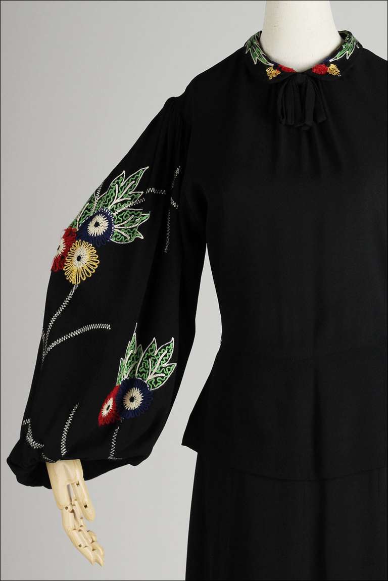 ➳ vintage 1940's dress

* black rayon crepe
* floral embroidered sleeves/collar
* peplum waist
* metal snaps at cuffs
* button back
* metal side zipper

condition | excellent

fits like large

length 45