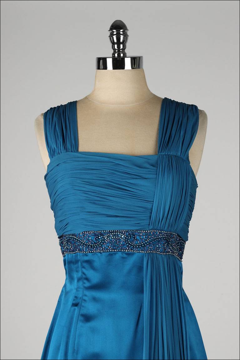 ➳ vintage 1950's dress

* sapphire silk crepe/satin
* acetate lined bodice
* mesh lined skirt
* shirred bodice
* side sash attached at hem
* beaded/rhinestone waist
* metal back zipper
* by Parnes Feinstein

condition | excellent

fits