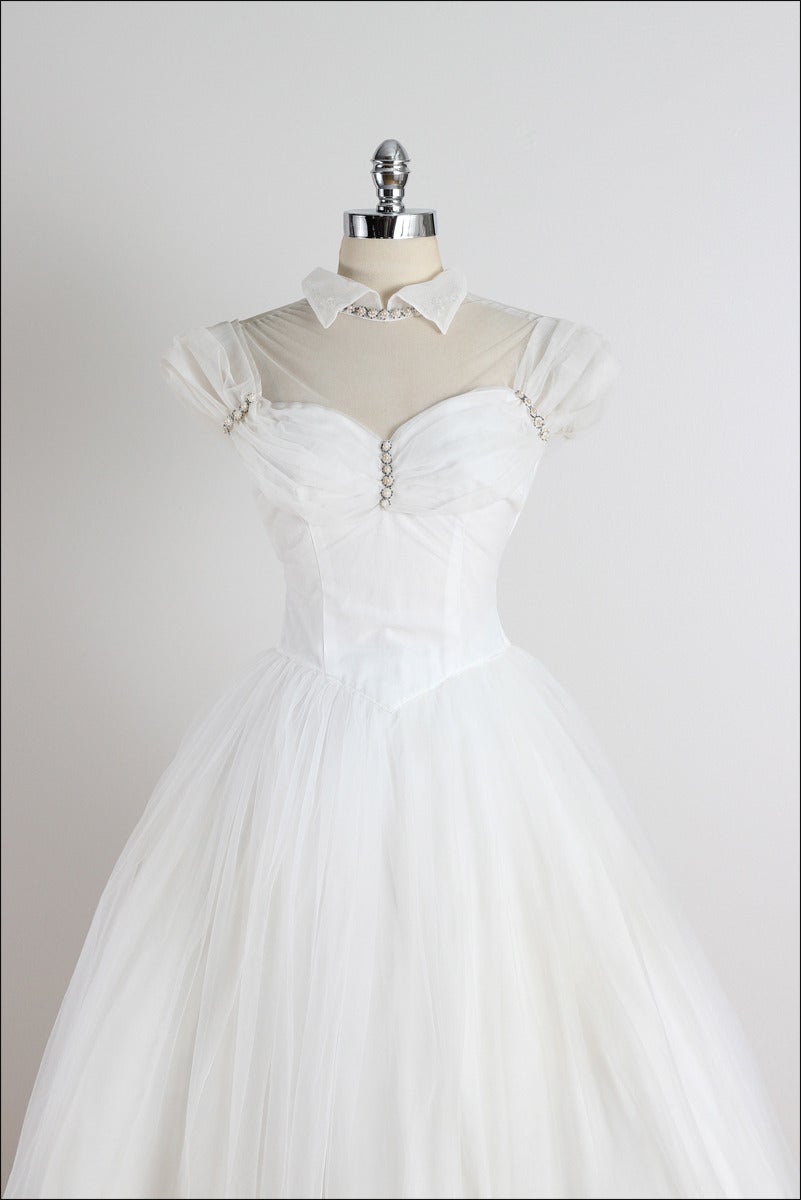 ➳ vintage 1950s wedding dress

* gorgeous white tulle
* acetate lining
* nude illusion bodice
* amazing pearl & beaded accents
* gathered bodice & shoulders
* button back

condition | excellent

fits like xs/s

length 52
