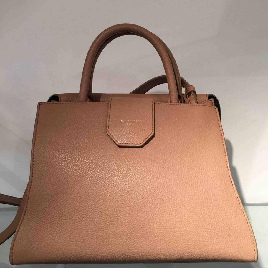 
Givenchy calfskin satchel bag. Shiny palladium hardware. Tubular top handle; 3.5 drop. Adjustable shoulder strap; 16.75 drop. Flap front with turn-lock bar detail. Back open compartment with tab closure. Lambskin lining and interior pocket.