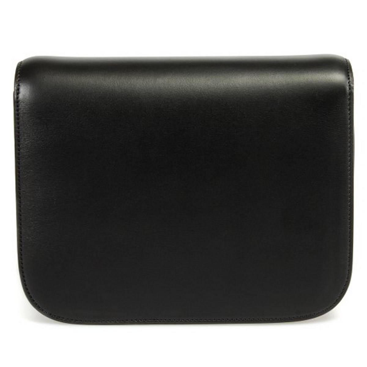 Seamlessly understated this Céline Box Shoulder Bag in size medium is constructed from high quality black calfskin leather. The bag features a unique push tab closure in gold hardware revealing the Céline logo imprinted on the interior tab. This