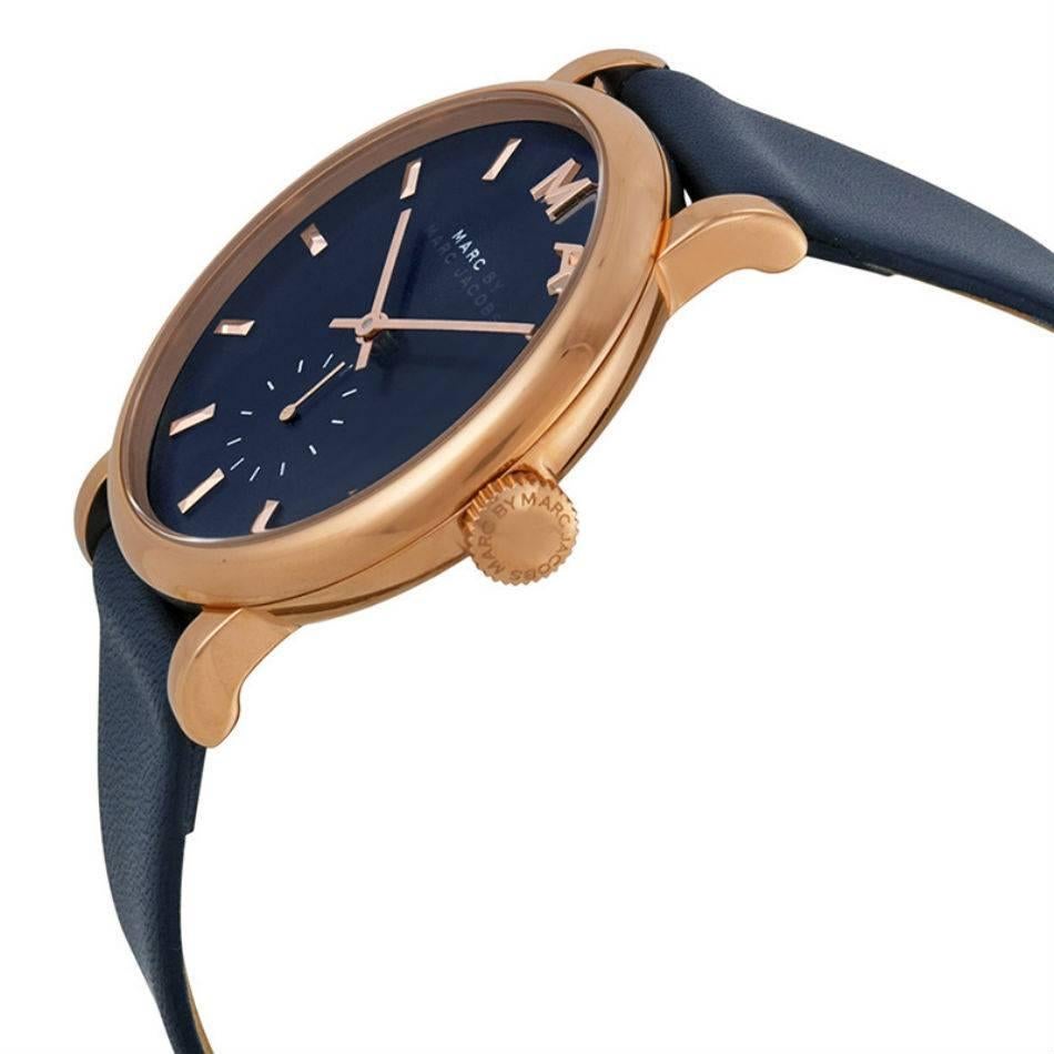 Rose gold-tone stainless steel case with a navy leather strap. Fixed rose gold-tone bezel. Navy dial with rose gold-tone hands and index hour markers. Dial Type: Analog. Seconds sub-dial at the 6 o'clock position. Quartz movement. Scratch resistant