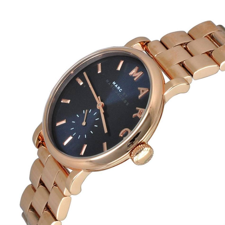 Rose gold-tone stainless steel case and bracelet. Fixed rose gold-tone bezel. Navy dial with rose gold-tone hands and index hour markers. Dial Type: Analog. Small seconds sub-dial at the 6 o'clock position. Quartz movement. Scratch resistant