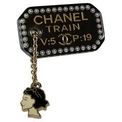 Broche Chanel RARE « COCO TRAIN TICKET » EN RÉSINE NOIRE AVEC PENDENTIF