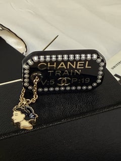 SELTENE SCHWARZE COCO-BROCHE VON CHANEL AUS KUNSTHARZ IN ZUGFAHRKARTENFORM MIT ANHÄNGER
