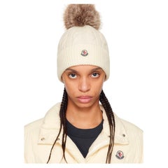 Bonnet Moncler à pompon en fourrure. Un pull de luxe emblématique pour l'après-ski. Blanc / Crème.
