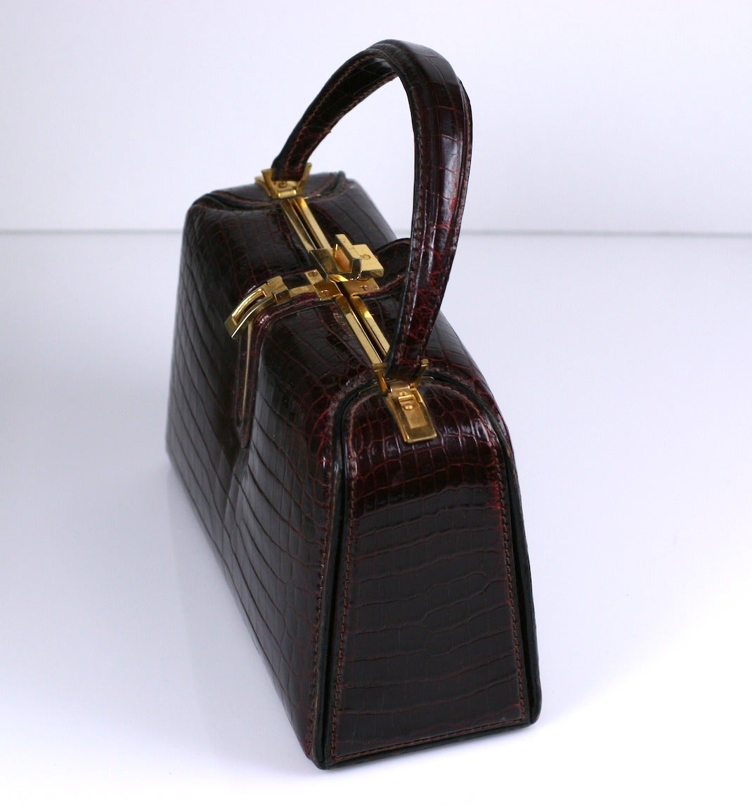 Wonderful bordeaux alligator box bag by Fernande Desgranges, Paris. Elegant and chic in a 60's-70's manner with incredible detailing and finishes. A twist of the clasp opens the bag completely for easy access. Lined in matching bordeaux calf.
The