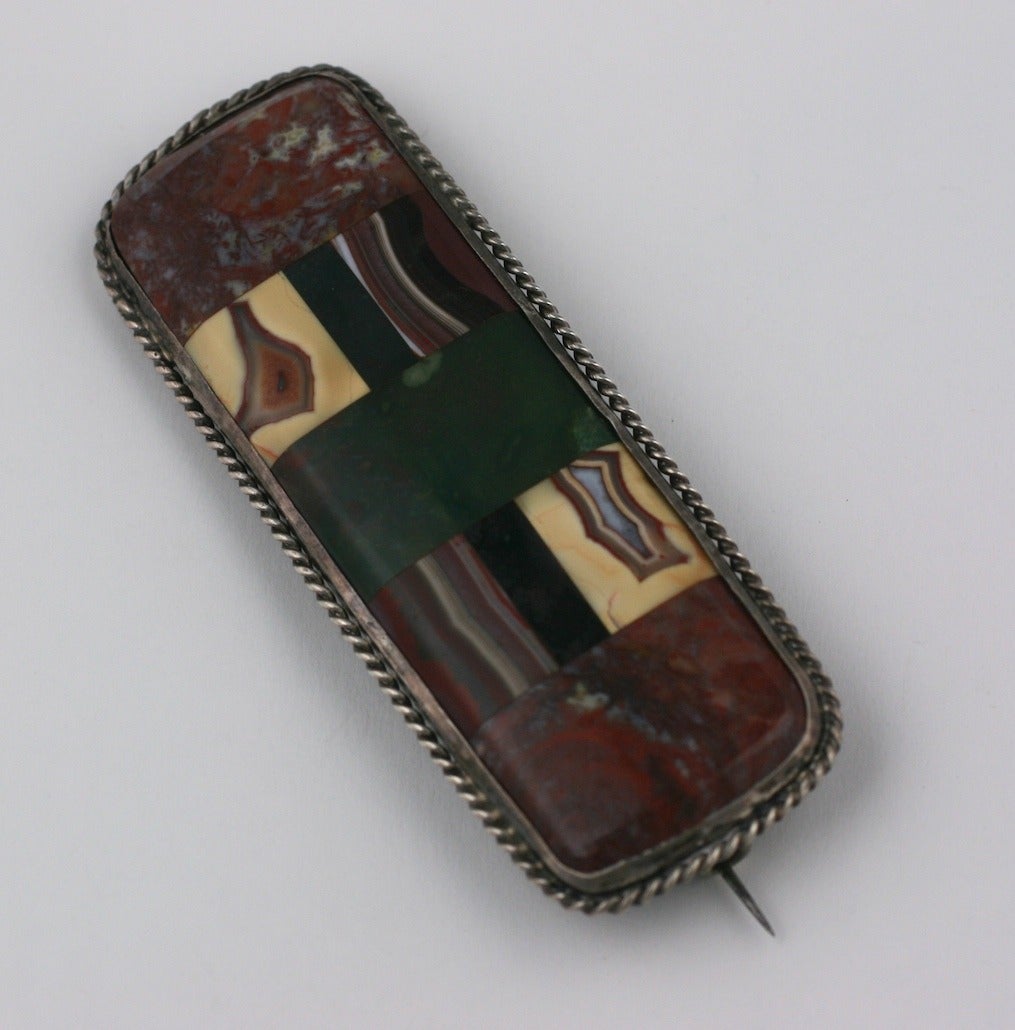 Lovely Scottish agate brooch from the late 19th century. Decorative agate specimens are inlaid over a stone base and then set into a sterling surround. The bezel is made of twisted sterling wire with period 