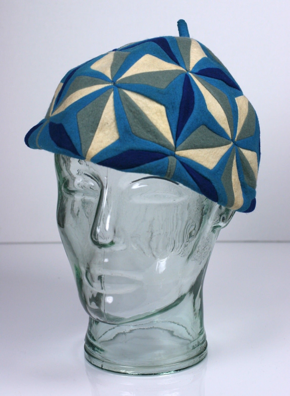 The Italian doll company Lenci occasionally made small fashion accessories such as this beret from the 1930's. This elaborate hand pieced patterning is highly evocative of Cubism and the Art Deco era in shades of blues, grays and white wool felt.