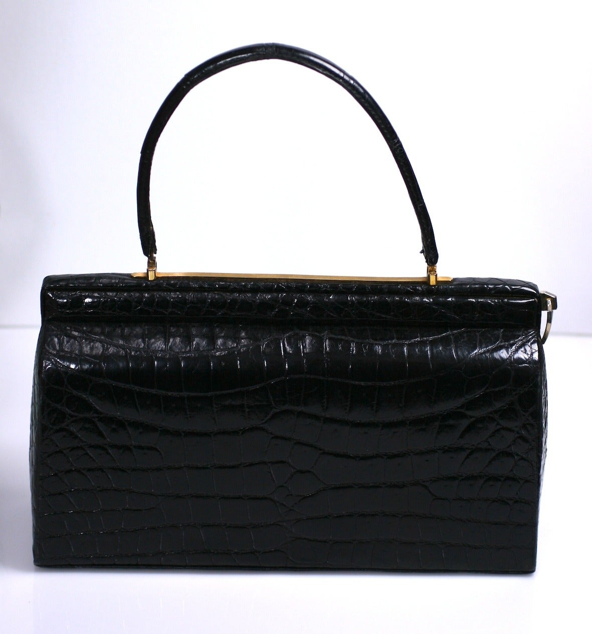 Elegant 1950's French alligator bag of elongated form with unusual pull tab access.
Pulling the decorative tab at end of frame unlocks mechanism. Frame can then be snapped shut manually. 
Attractive rectangular form is timeless and roomy. 1950's