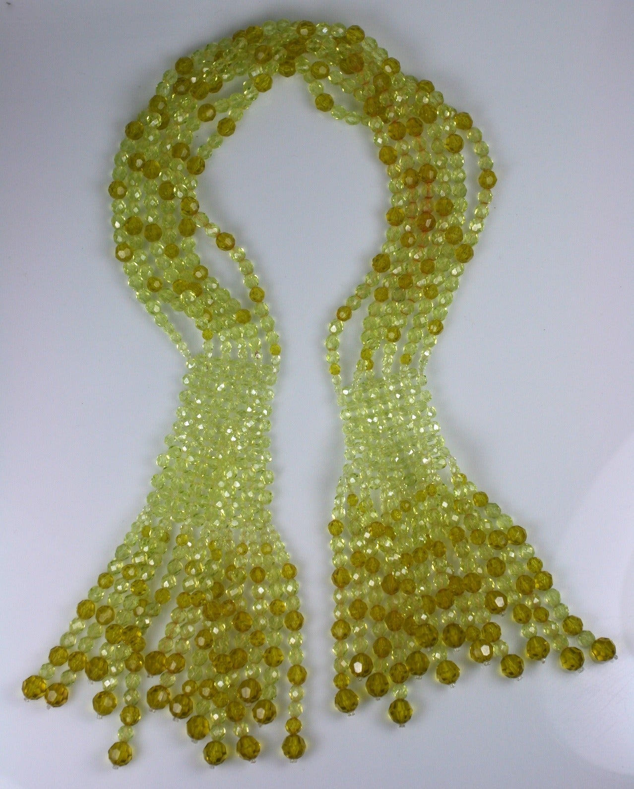 Coppola e Toppo shaded chartreuse crystal beaded crossover scarf necklace. Unusual vaseline coloring with tonal shading. The graduated beads are woven together in sections which release into graduated larger strands in darker tones. Length  33