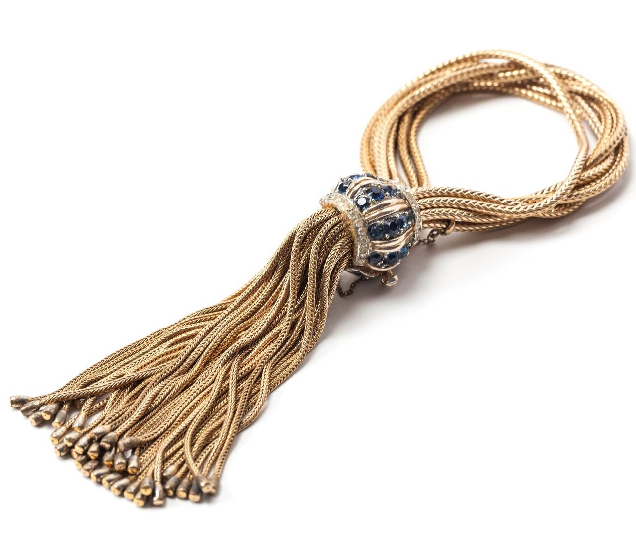 Amazing Boucher Retro Tassel Bracelet from the 1940's. A series of gilded fox chains are used to form the bracelet and faux tassel which falls from the clasp studded with faux sapphires and pastes. 
Marcel Boucher was the creator of some of the