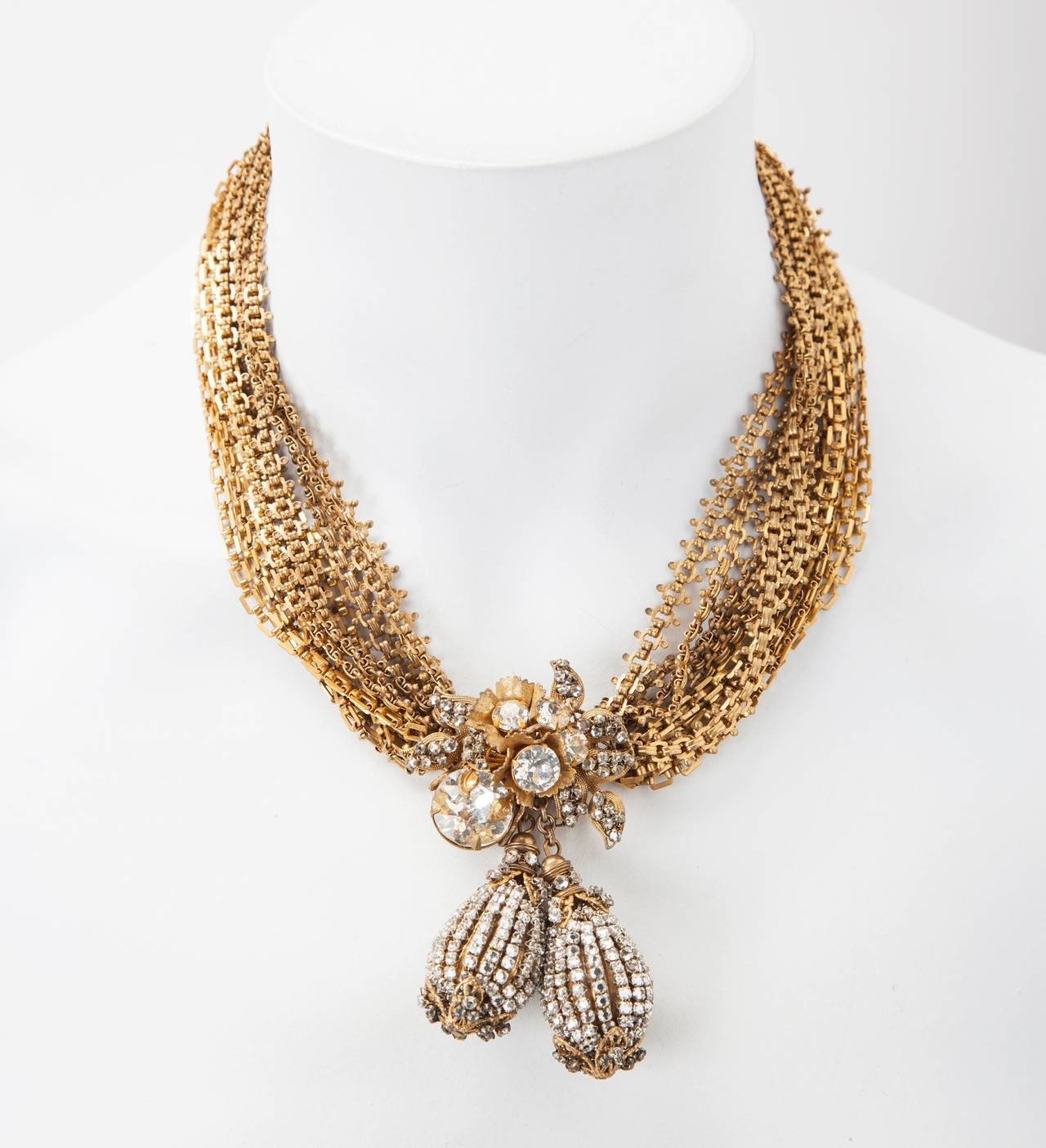 Elaborata collana a più catene in oro russo firmata Miriam Haskell con intricati lavori di pavé di cristalli montati su filigrane dorate. Ciondolo focale con doppie gocce pendenti a forma di pera di cristallo minuto cucito a mano che cadono da un