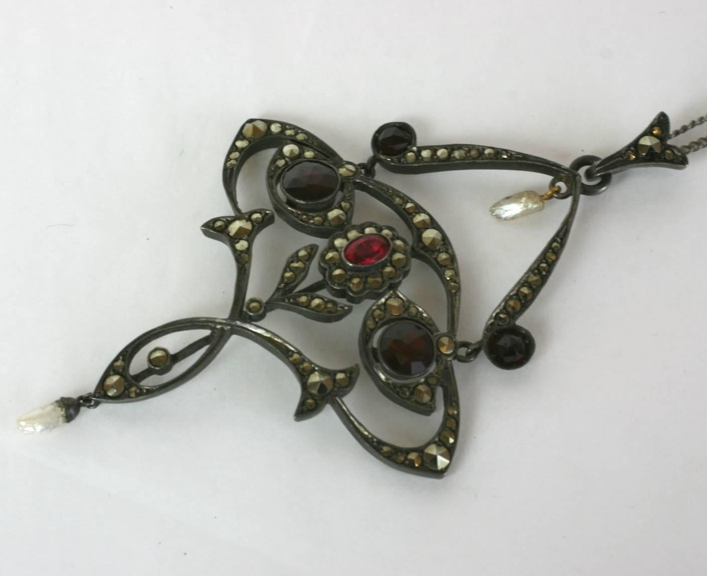 Lovely Edwardian Marcasite and Garnet Pendant of openwork sterling silver with Art Nouveau influences. Marcasites are set throughout with a central closed backed oval garnet and 2 flanking round garnets in unusual rose cuts. 2 tiny freshwater tooth