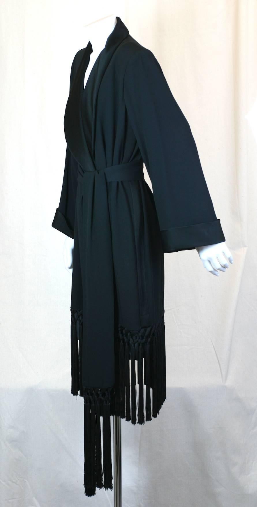 Yves Saint Laurent fringed crepe tuxedo dress. 
Easy, straight cut falling from strong shoulders with large bell cut sleeves with satin cuffs. Wrap style dress with long fringed detail applied on hem and sash. Wide shawl collar, cuffs and tuxedo