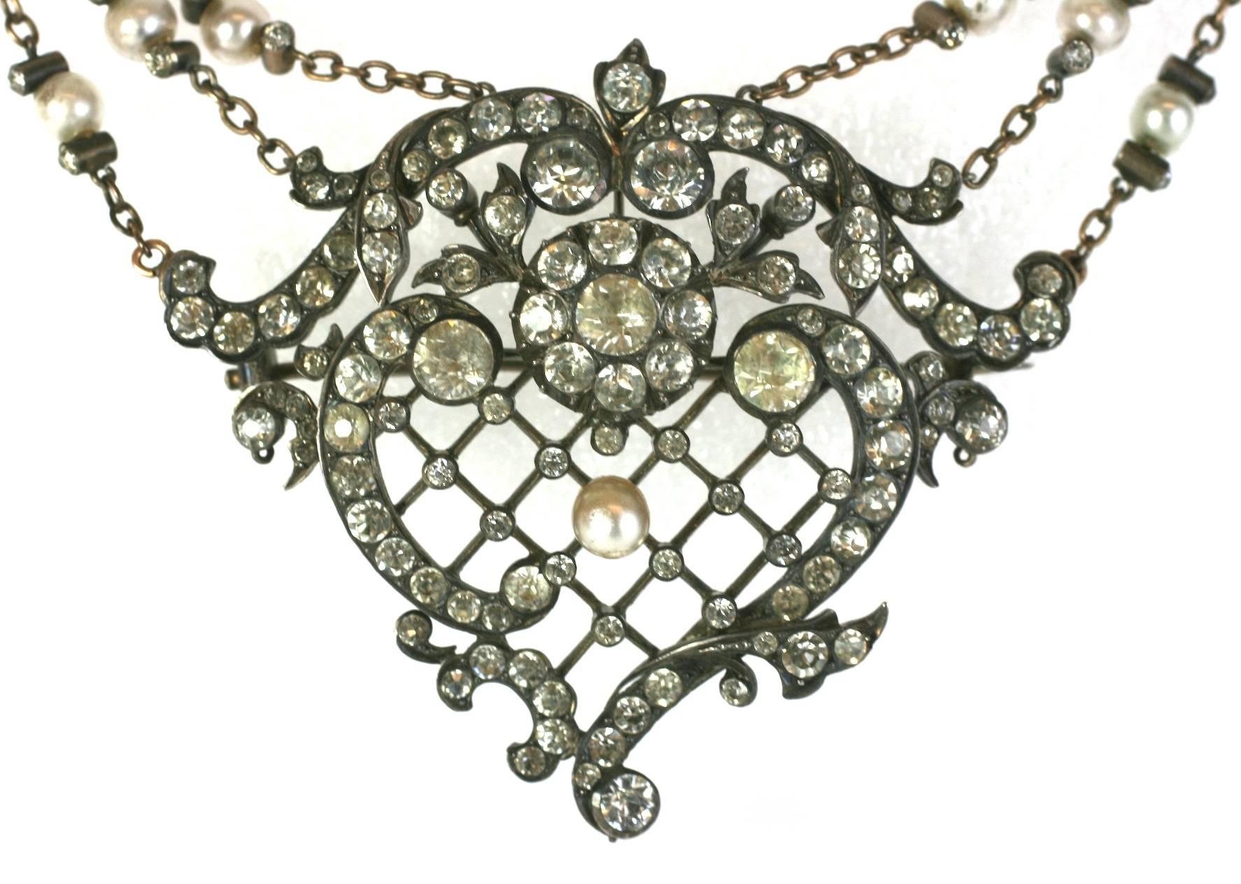 Exceptional Edwardian Corsage Ornament set in silver with pastes. Lovely design with central motif held by 3 sets of paste and faux pearl set swag chains, hanging off sword hilt motifs. 
This piece was originally designed to be worn in the bosom of