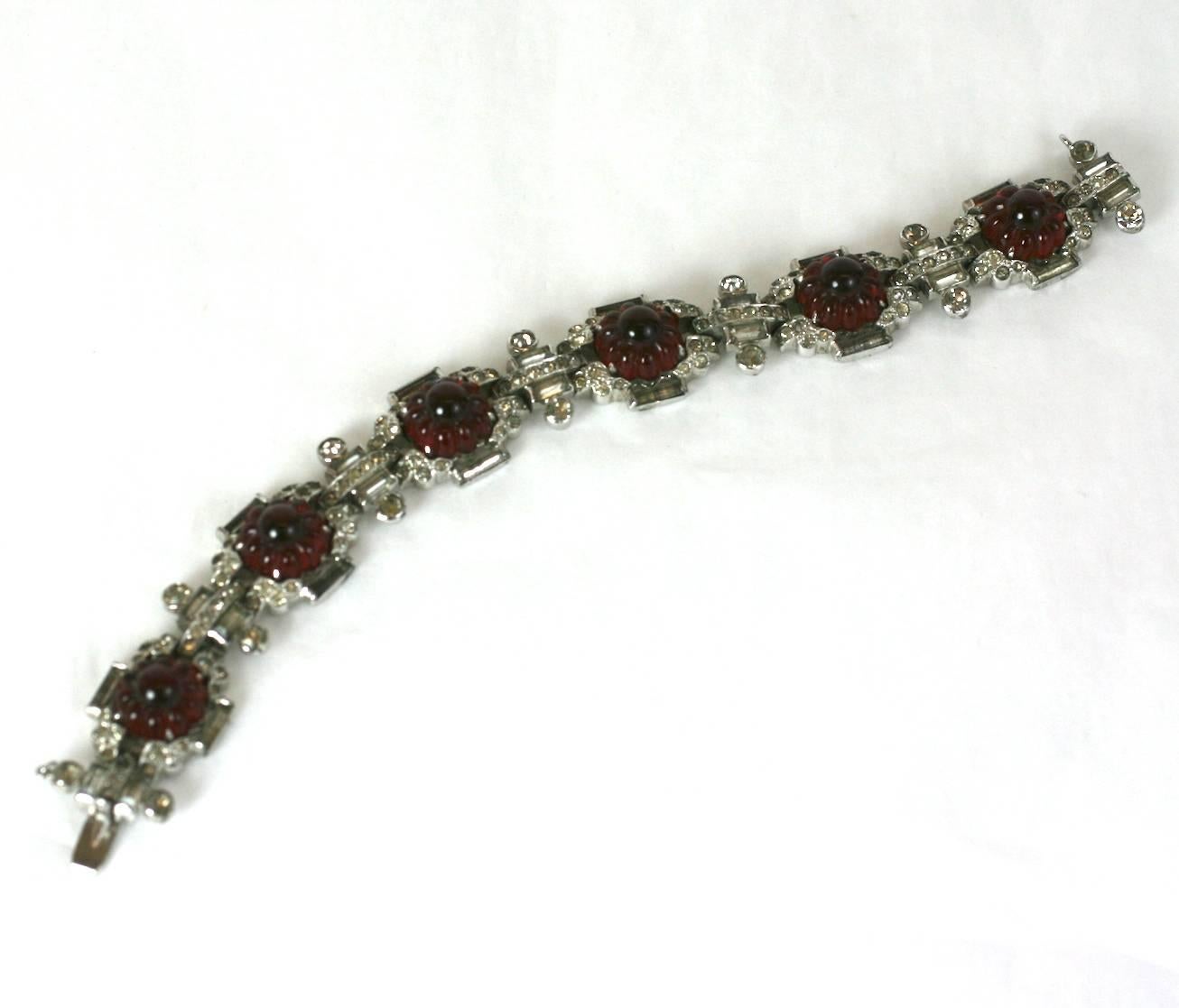 Bracciale a maglie con rubini finti e cristalli in metallo placcato in rodio. Rubini finti modellati a gelatina e incastonati in un elaborato disegno deco di diamanti finti. Anni '20, USA. Condizioni eccellenti. Firmato KTF.
Lunghezza 7