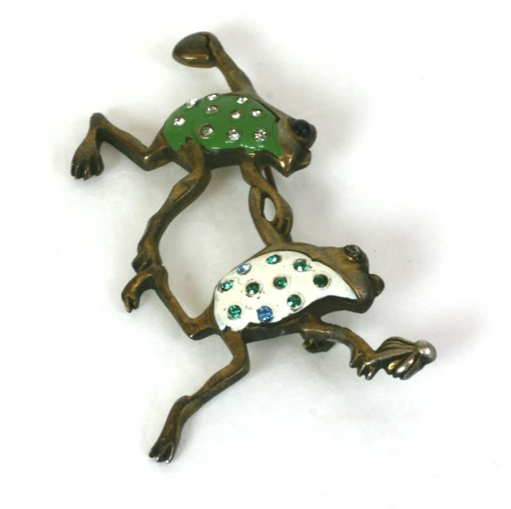 Amusing, frolicking and prancing figural frogs brooch of gilt metal and cold enamel in green and white with multicolor crystal pave accents.
Excellent Condition. 1930's USA.
Length 2.50