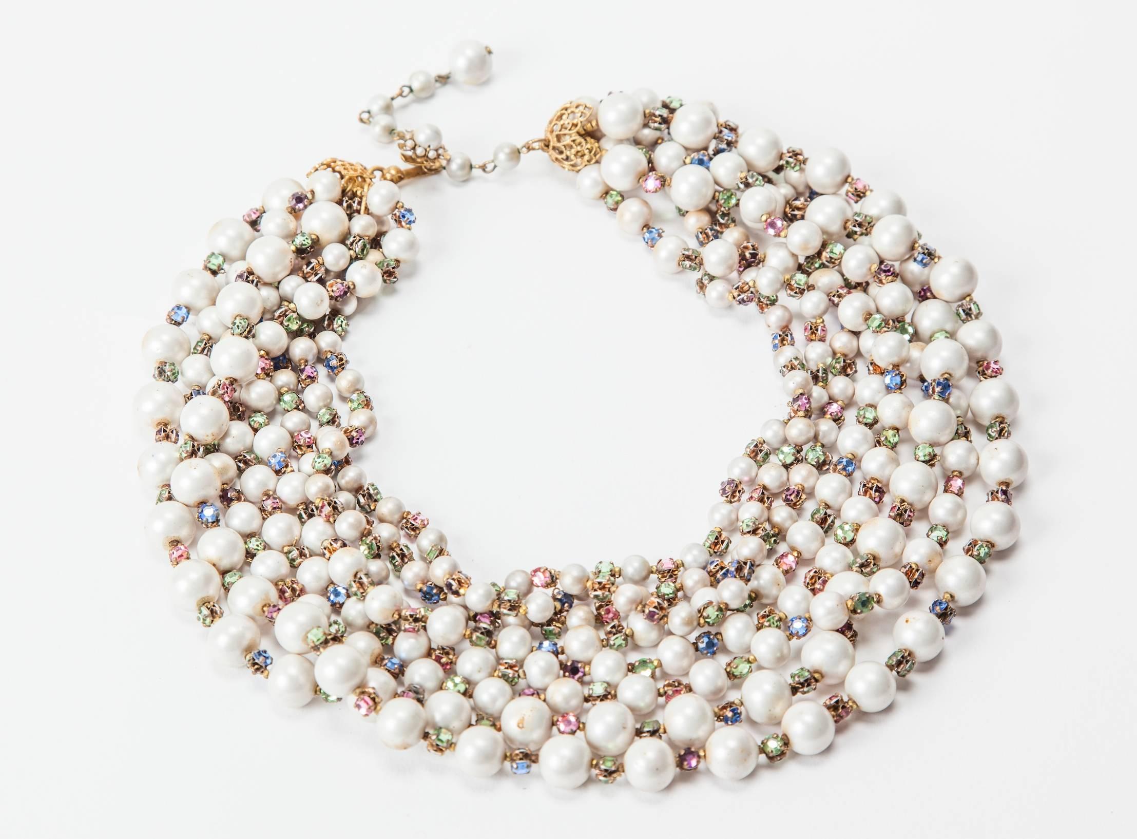 Wonderful Miriam Haskell eight strand draped necklace of signature Freshwater faux pearls. Each freshwater pearl bead spaced by hand sewn, vari colored pastel  rose monte crystals.The staggered strands terminate in signature Russian Gilt filigree