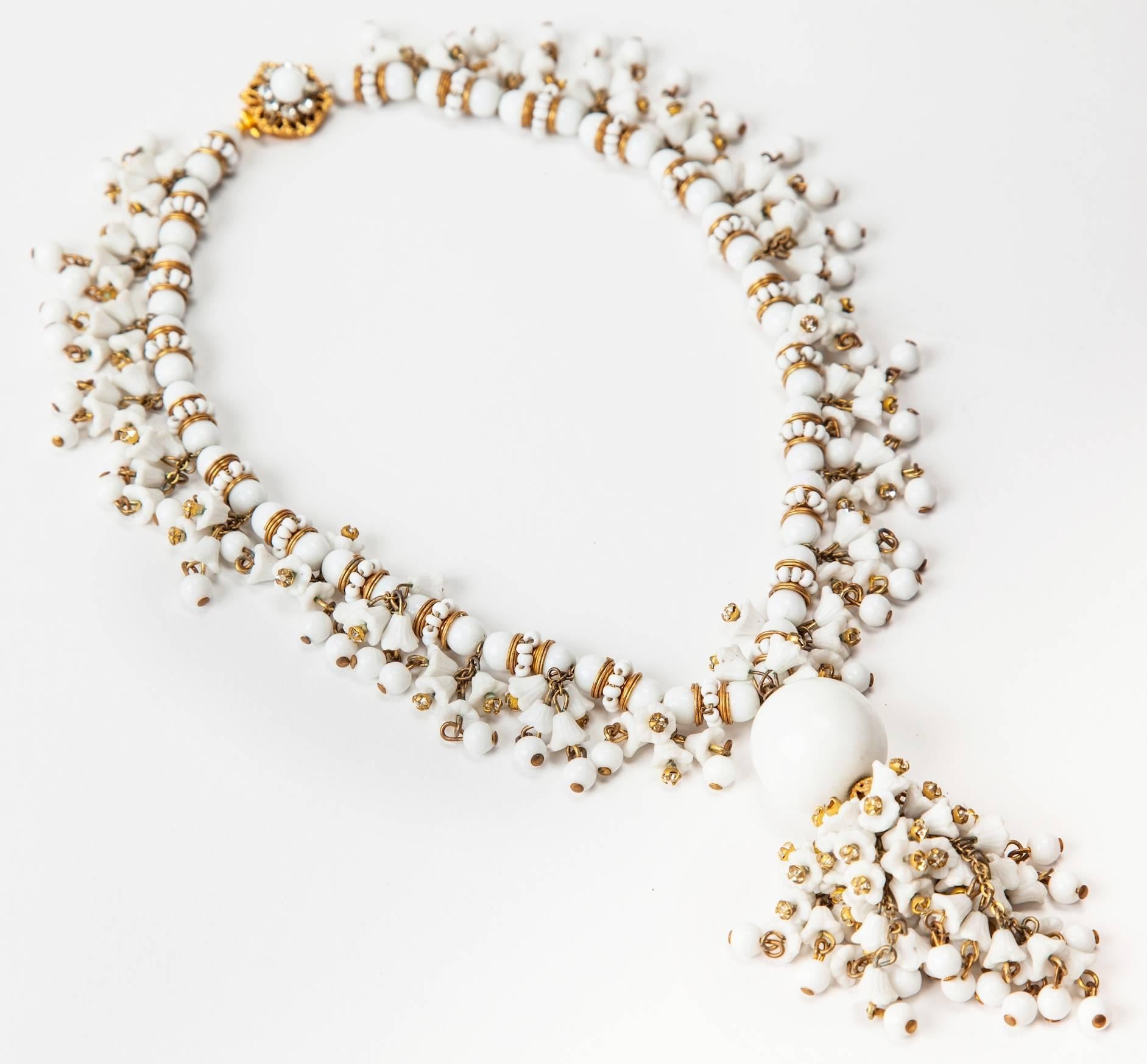 Miriam Haskell elaborata collana fatta a mano con fiori a campana e perline rotonde in vetro al latte. Ulteriormente impreziosito da distanziatori dorati russi, gocce di vetro al latte e rose di cristallo su una classica chiusura Haskell decorata.