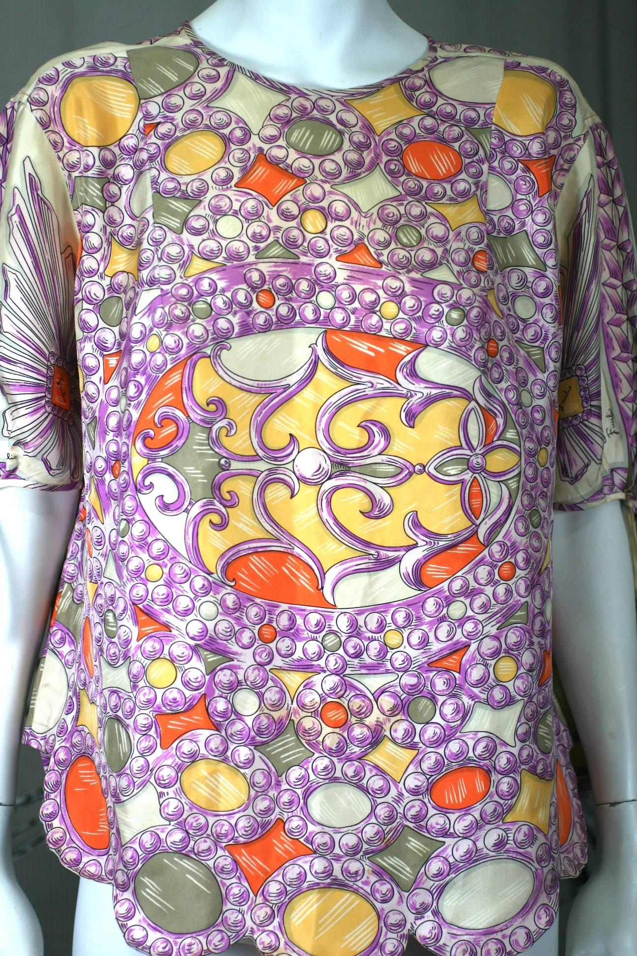 Emilio Pucci Jewel Print Top of silk twill printed with a design of intarsia stones or jewels in purple, orange and yellow. Short sleeves have bias piped trim to tie in a bow as does neckline.
Hem is scalloped with design of pattern. 1960's Italy.