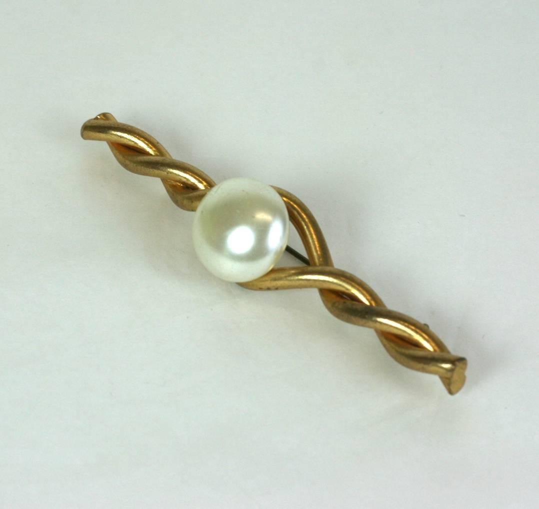 Épingle à barrette en bronze doré et perles classiques de Coco Chanel par Robert Goossens pour Chanel.
Composé d'un fil doré torsadé avec un cabochon en fausse perle. Chanel a souvent été photographiée dans des variantes de cette broche. Tout