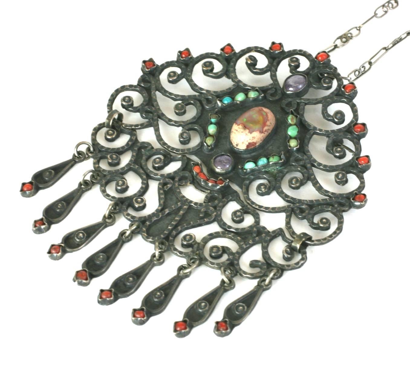 Elaborate Mat'l Style Sterling and Stone Pendant Necklace set in sterling silver. Large articulated pendant set with a large Mexican opal, red coral, amythest and turquoise. Handmade sterling swirl bar chain. Made in Mexico, circa 1950.
Signed