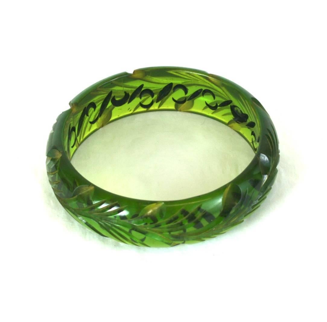 Green Apple Juice Bakelite Carved Bangle with unusual undercarving and staining. Leafy vine designs are carved on the exterior and swirls are carved inside and patinaed black. High contrast design with interesting final effect.
1930's USA.