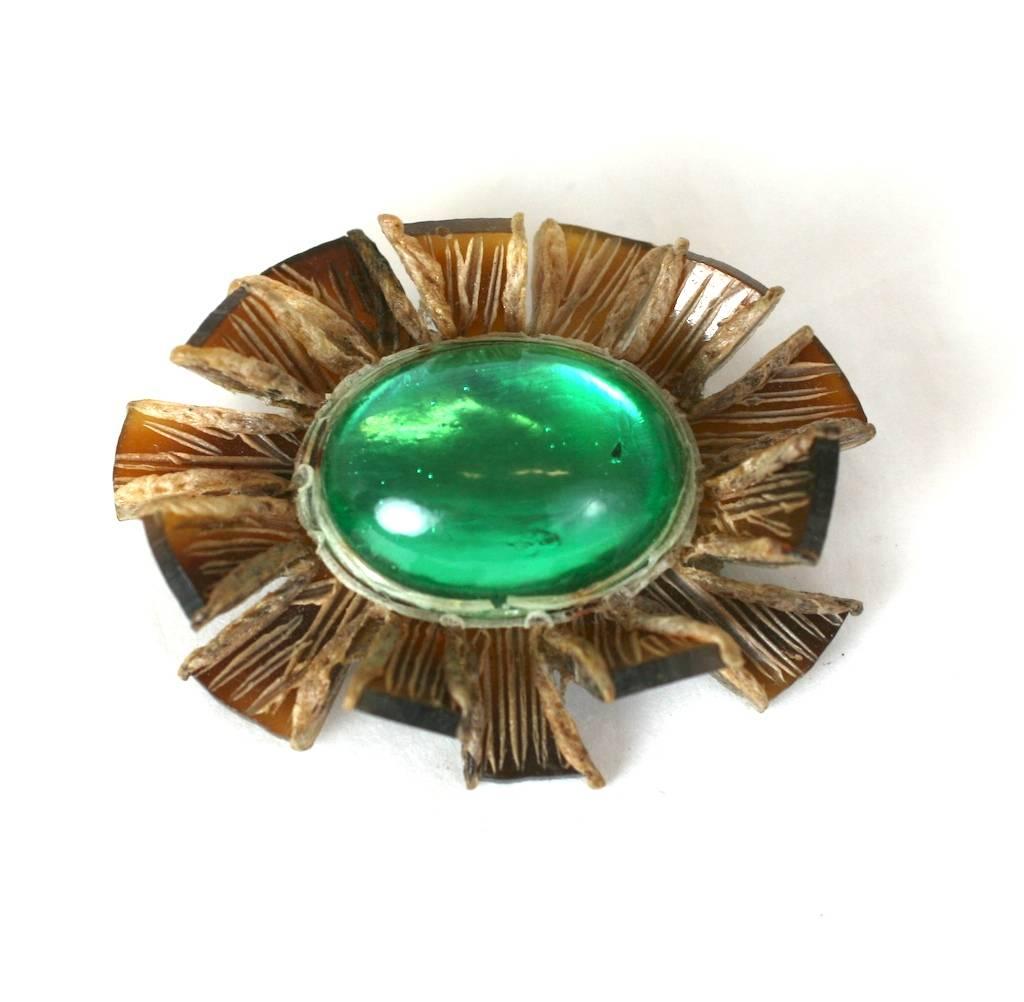 Talosel resin brooch with large pate de verre Cabochon. Designed in an oval form, the warm resin has been scored, cut and pleated to form a dimensional pin wheel style border. A glass cabochon in brilliant emerald green rests at the center. French,