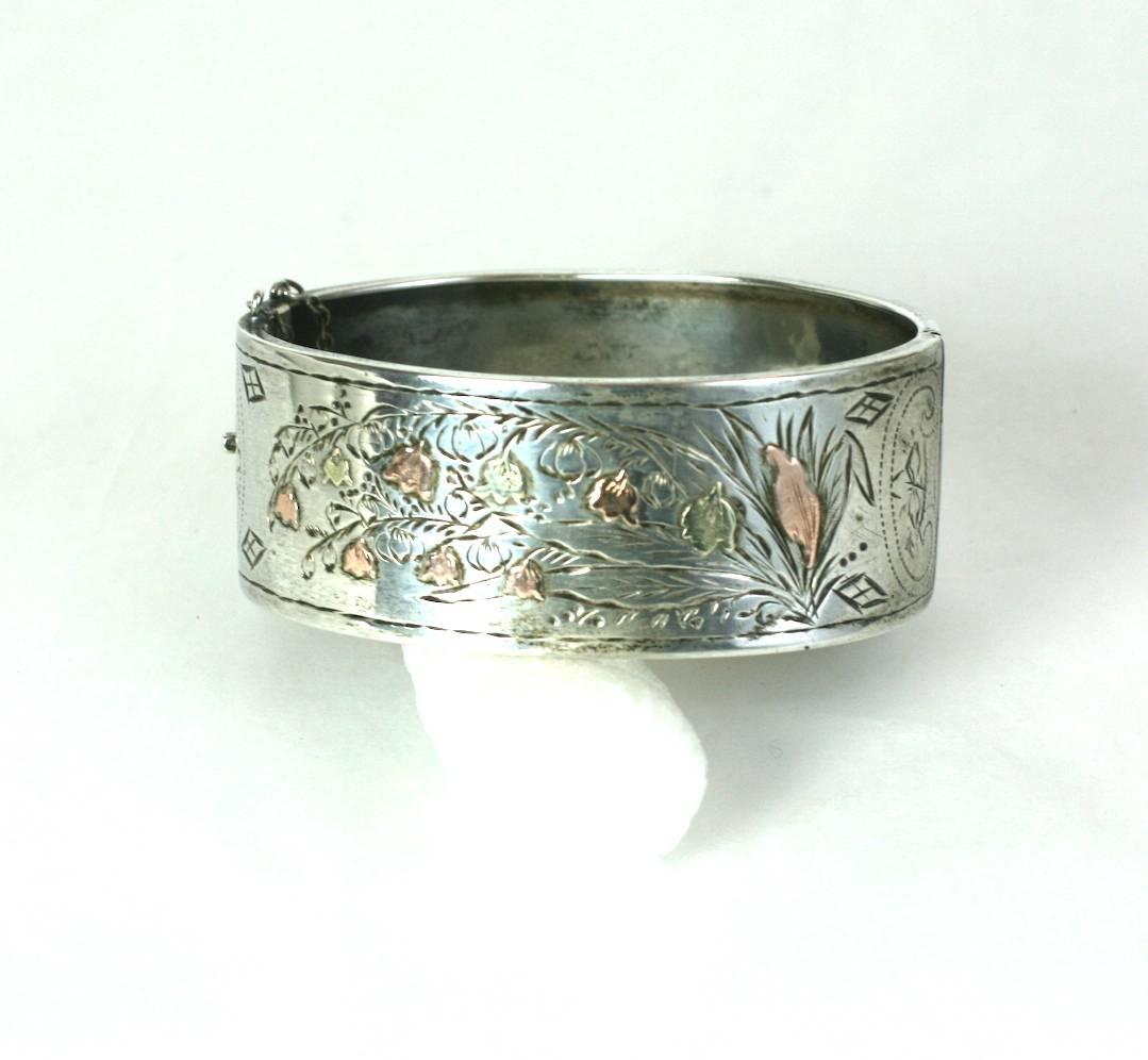 Victorian Mixed Metal Lily of the Valley Bangle form the late 19th Century.
Sterling bangle with applications of pink and green gold florals which are applied over the engraved design. 
1