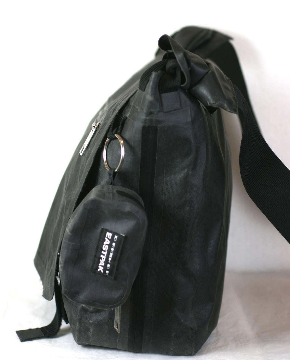  Rick Owens Resinated canvas Messenger bag, by Eastpak x DkShdw. 
Large scale messenger bag with expandable zipper on base. Flap fastens with 2 velcros straps for security. Open storage slot in back, with dangling key purse on side. Interior also