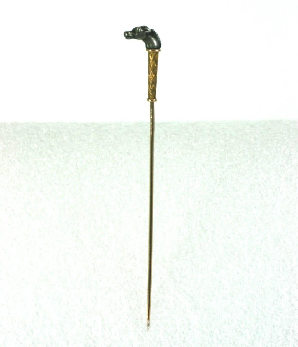 Epingle de Stick à tête de cheval victorienne conçue comme un bâton miniature. La tête de cheval finement détaillée est en sterling avec un œil en diamant taillé en rose. La garde en dessous a des détails complexes de vannerie en or. La tige de