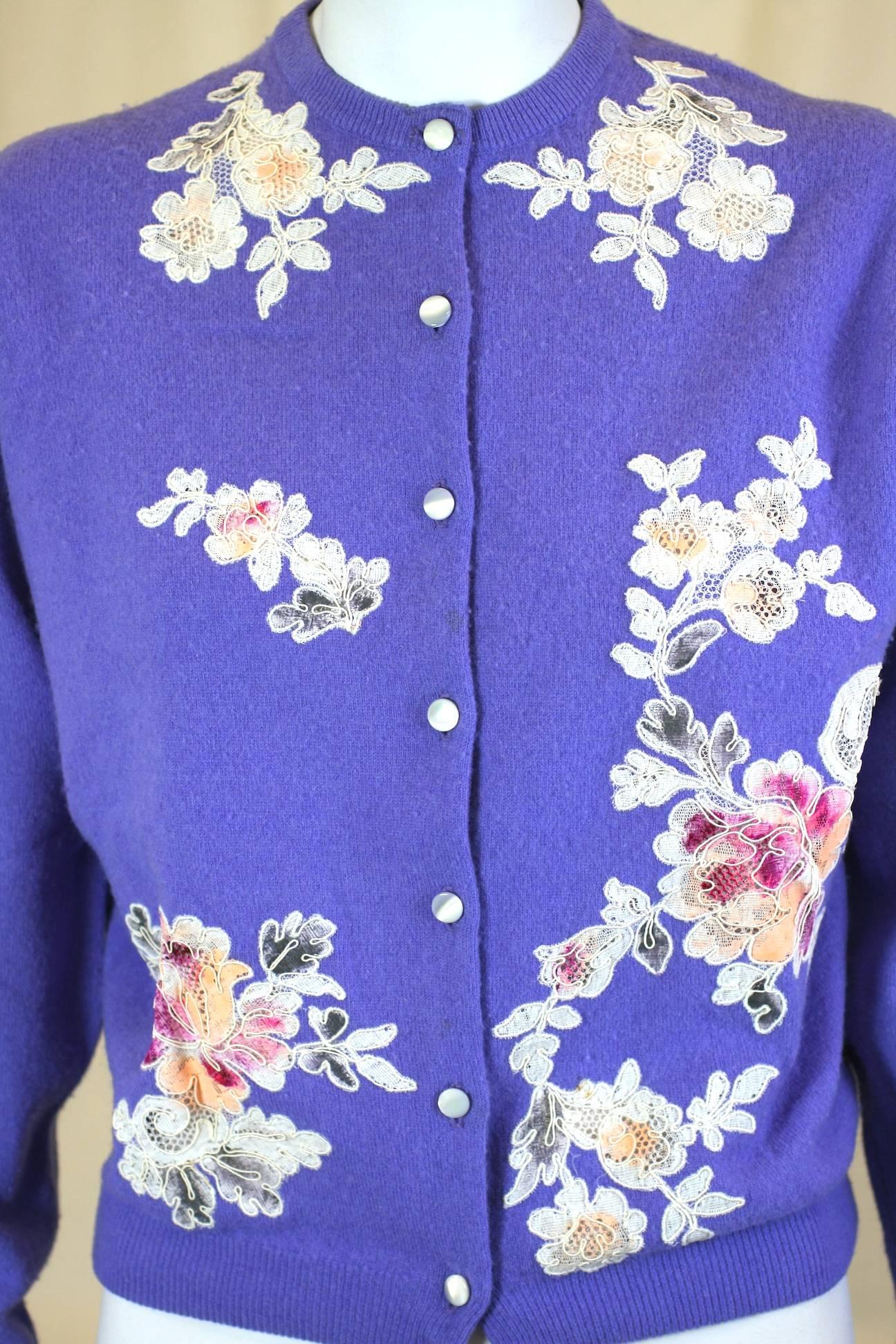 Lovely Purpley blue Cashmere Cocktail Cardigan with lace decoration by Stylecraft of Miami. Hand cut lace appliques are high lighted with colorful hand painting and then applied to the cashmere base. Body lined with pink chiffon with faux mother of