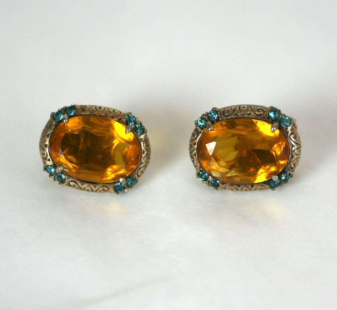 Ciner Retro faux topaz ear clips with faux aquamarine paste accents, all set in engraved gallery of gold washed sterling silver. Clip back fittings. 1940's USA.
Excellent Condition. 
Length .75