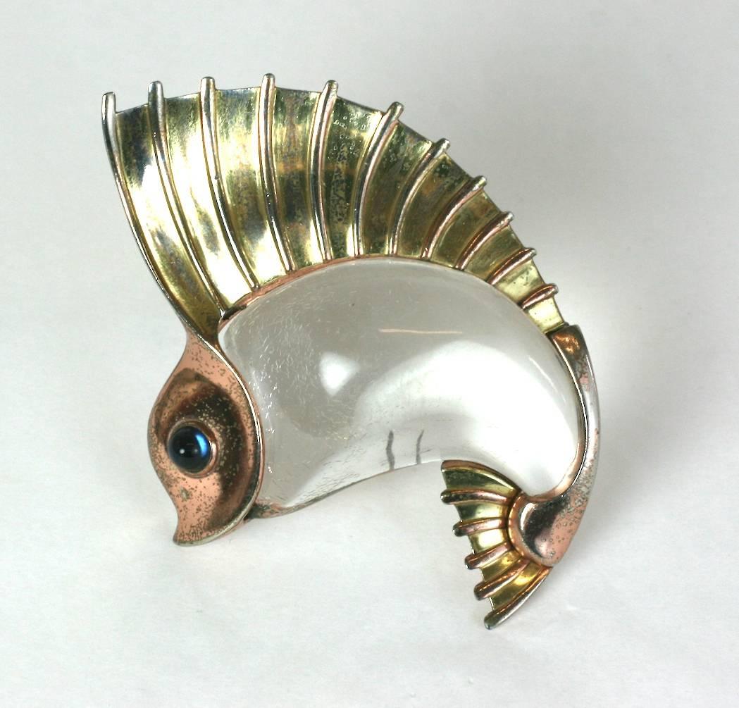 Rare Trifari Norman Bel Geddes Jelly Belly fish brooch designed in 1941.
This Jelly Belly Sailfish Clip-Brooch is formed of a yellow and rose gold plated base metal alternating to form the tail fins segments, with a clear lucite 