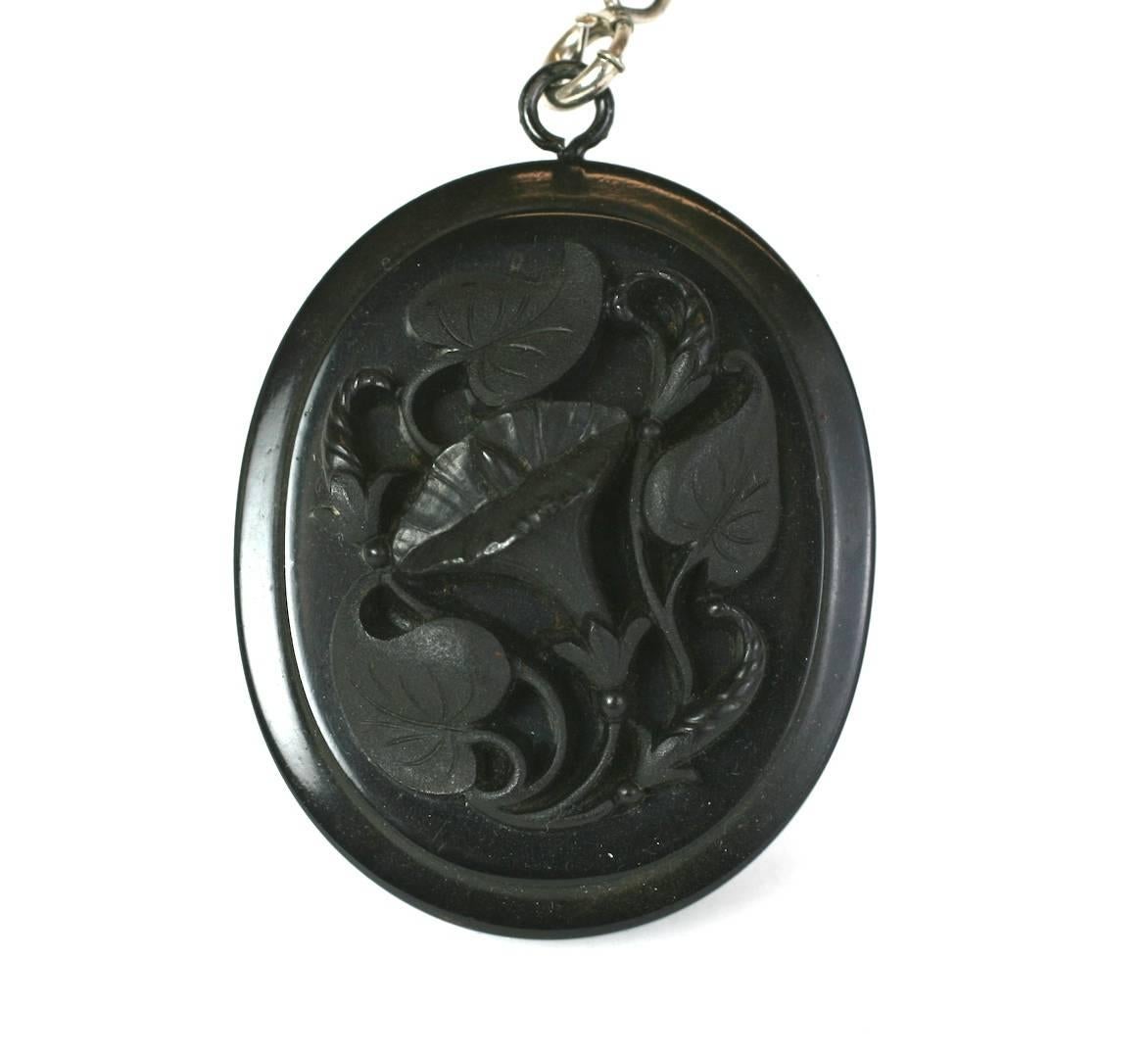 Guttaperca vittoriana  Collana con ciondolo, 1880 circa. Il ciondolo ovale è finemente intagliato con un motivo di gloria mattutina all'interno di foglie circostanti. Nastro originale in faille e regolatore a scorrimento in metallo