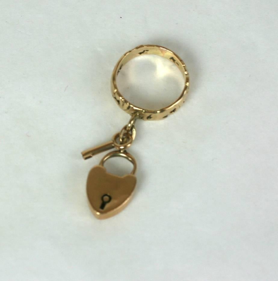 Charming Lock and Key Ring made from late 19th Century elements in 14k gold. An antique padlock and key dangle from a pierced band of intricate scroll work. 
Small size 4, US. 
New assemblage. Studio VL, designed to be worn on upper finger.