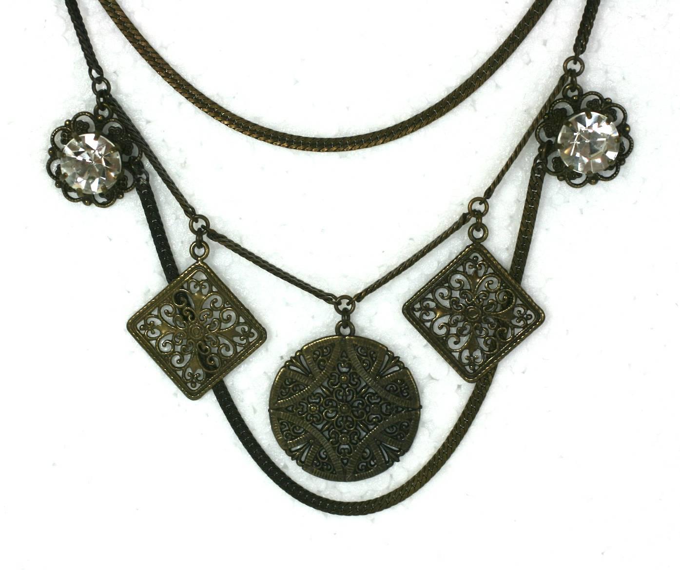 Broche Chatelaine, Nicole de Matsuda. Los colgantes con acabado en bronce antiguo están suspendidos de cadenas y de un par de pasadores de corbata tachonados con brillantes. Se puede llevar en el cuello o debajo, para conseguir un efecto de falso