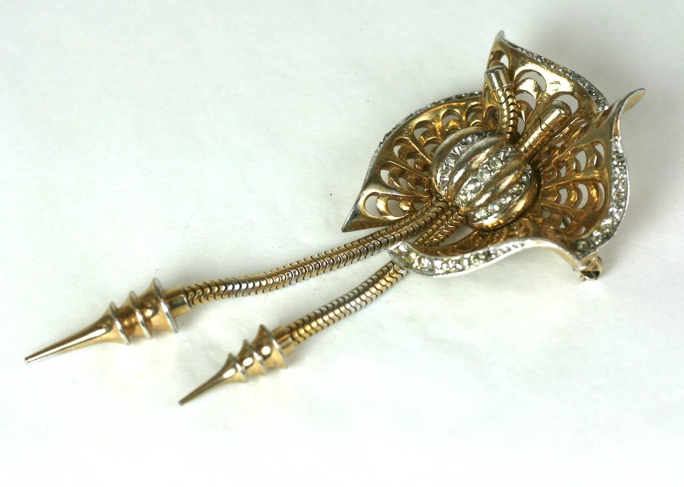 Marcel Boucher Retro brooch of gilt pierced metal. Pierced fan shaped scrolls are centered by focal ribbed pave ball with double pendant arrow drops, suspended by snake chains. 1930's USA. Early mark. 
Marked: MB (phrygian cap), Pat Pend, S.