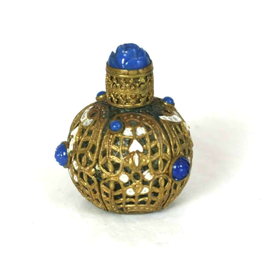 Czech mini  scent bottle wrapped with gold filigree panels. Each panel has a bezel set faux lapis pate de verre rose with white  cold enamel decoration. With gilt filigree and faux lapis cabochon cap and orginal glass dabber. 
Made in