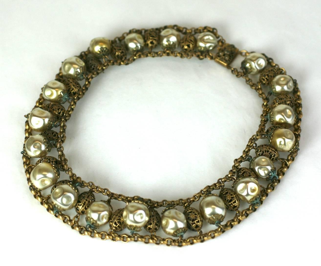 Collier tchèque surdimensionné en métal filigrané, perlé et doré, datant des années 1930. Finition martelée, fausses perles de verre creuses espacées entre des perles en filigrane doré montées sur une chaîne. Année 1930, tchèque. 
Excellent