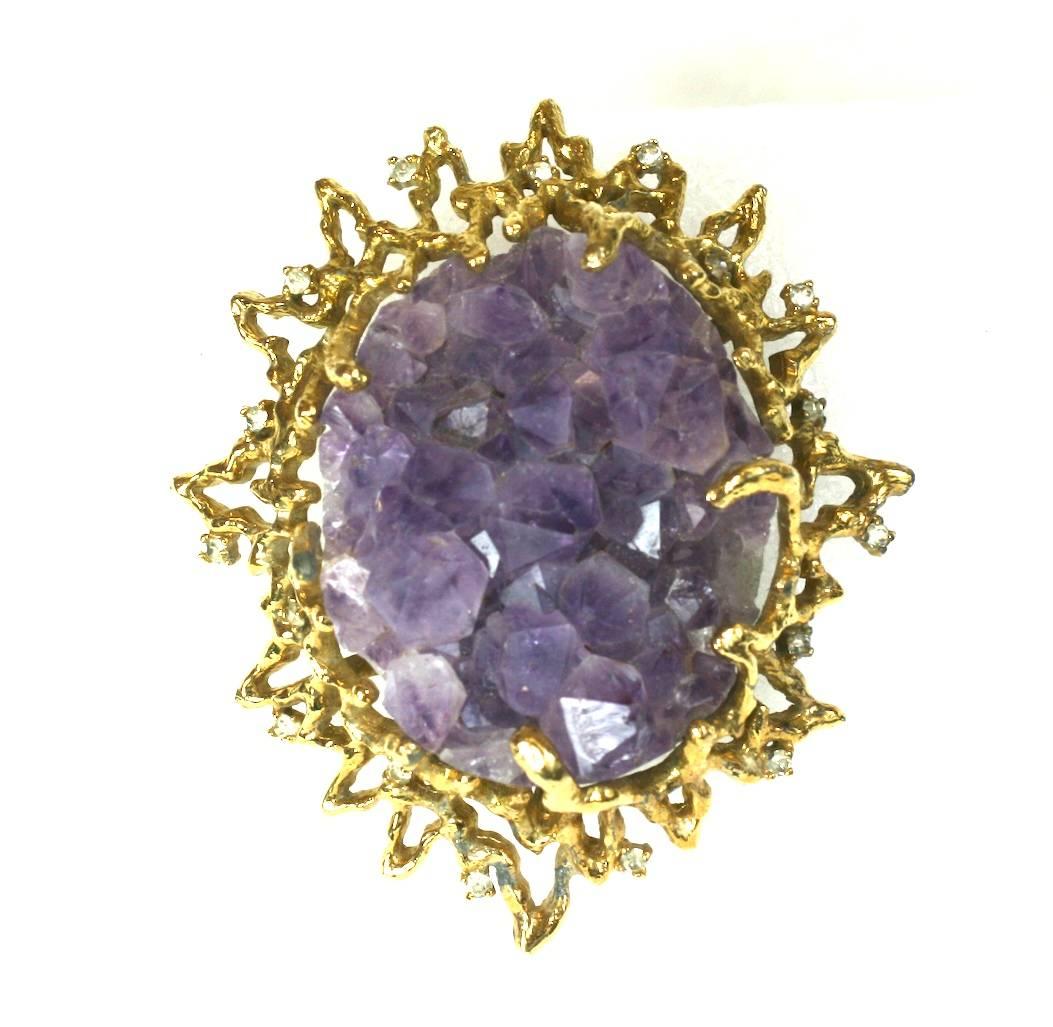 Jomaz Amythest Crystal Geode Pendant/Brooch from the 1970's. A large natural amythest crystal is set a dimensional, Brutalist gilt metal setting. Small crystal pastes accent the 