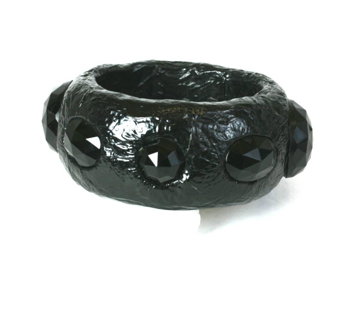 Wide handmade Artisan Paper Mache and Jet Bangle from the 1980's. Lightweight bangle is covered in black shiny cellophane and inserted with Victorian faceted black jet stones. Unusual and striking in its scale.
Width 1.5