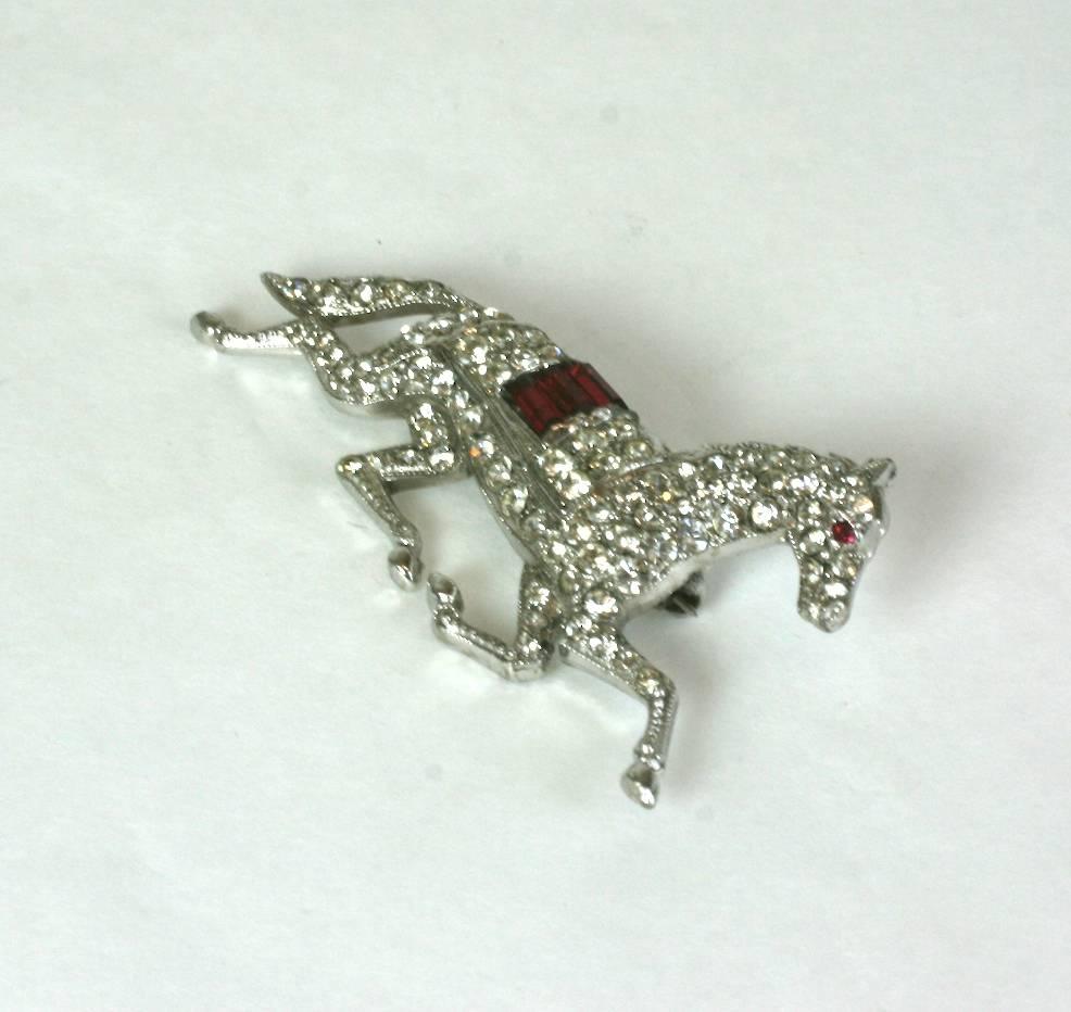 Charming, collectable Trifari crystal pave and faux ruby baguette galloping race horse brooch. Set in rhodium plated metal. The body of the horse of crystal pave with a faux ruby blanket. Signed KTF, 1930's USA. 
Excellent Condition
Length