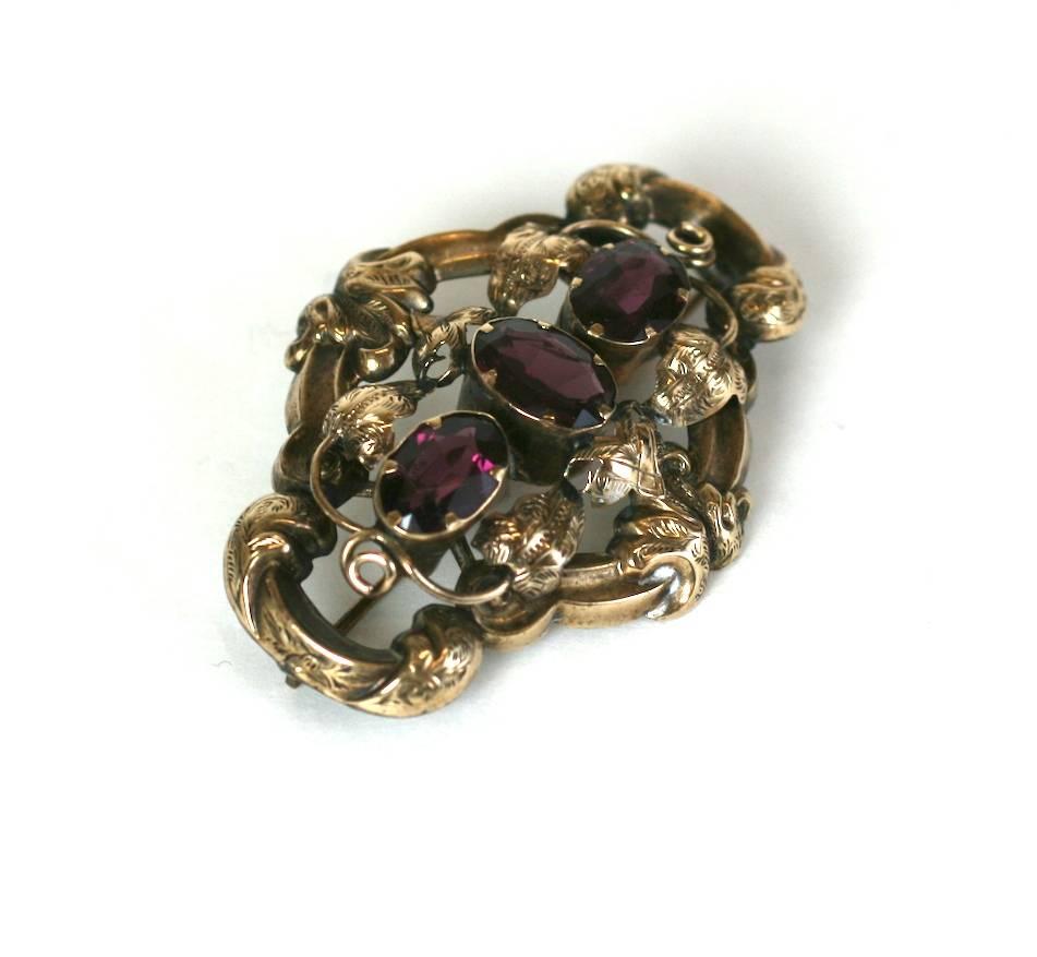 Victorian Gold Filled Garnet Brooch from the late 19th Century. Scroll work etched motifs and leaves surround 3 flat cut oval garnets. 1880's USA.
Very Good Condition. 
2