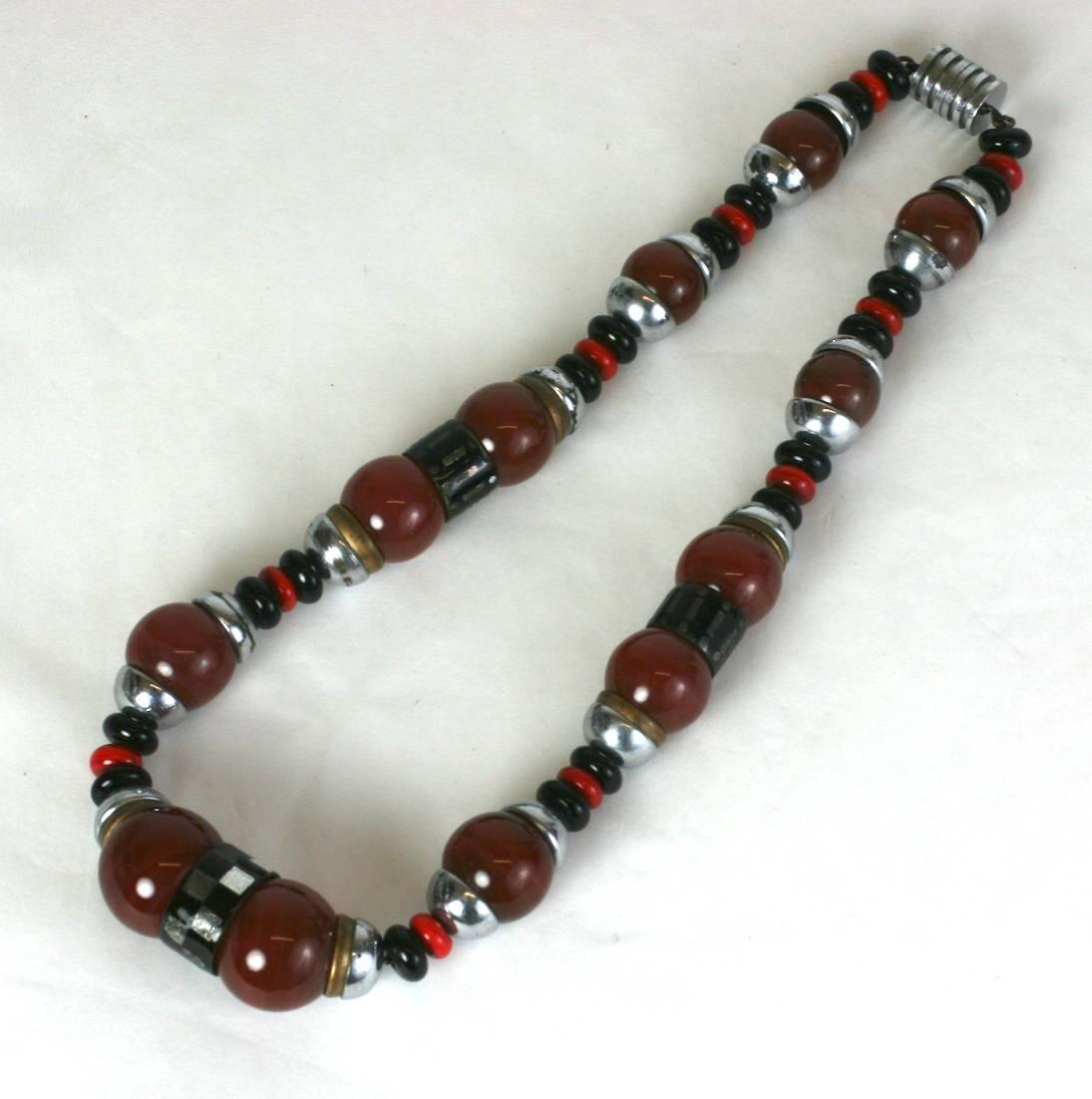 Art Deco Louis Rousselet Necklace of a robust Machine Age design. Composed of large round carnelian pate de verre beads,  jet and chinese rondelles with round stacked caps of gilt and silver plated metal, further enhanced by jet bakelite carved